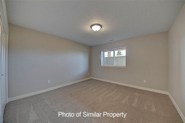 unfurnished room featuring carpet flooring and a textured ceiling