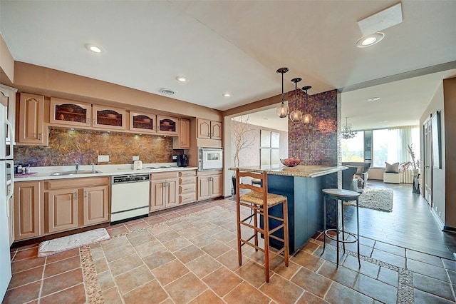 kitchen featuring a kitchen breakfast bar, white appliances, decorative light fixtures, and tasteful backsplash