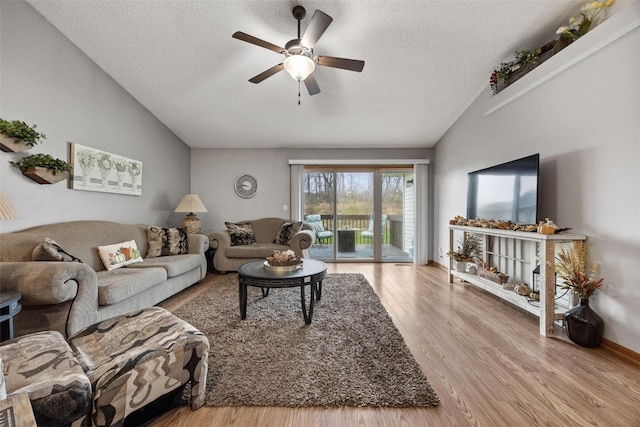 living room featuring a textured ceiling, ceiling fan, light hardwood / wood-style flooring, and vaulted ceiling