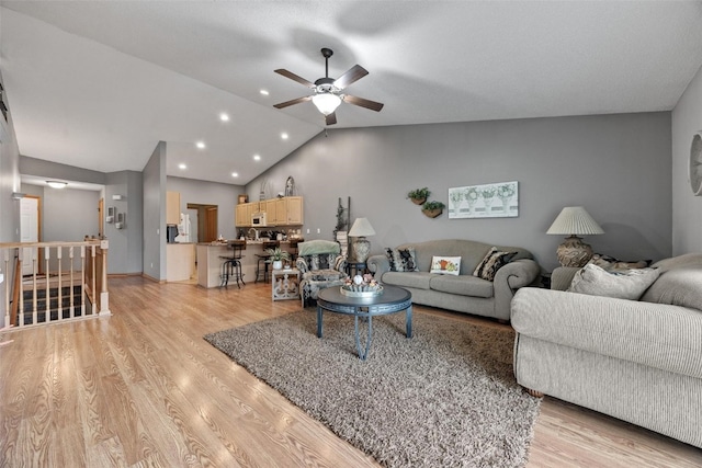 living room with light hardwood / wood-style flooring, vaulted ceiling, and ceiling fan