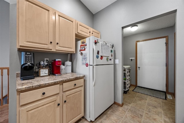 kitchen featuring light brown cabinetry and white refrigerator