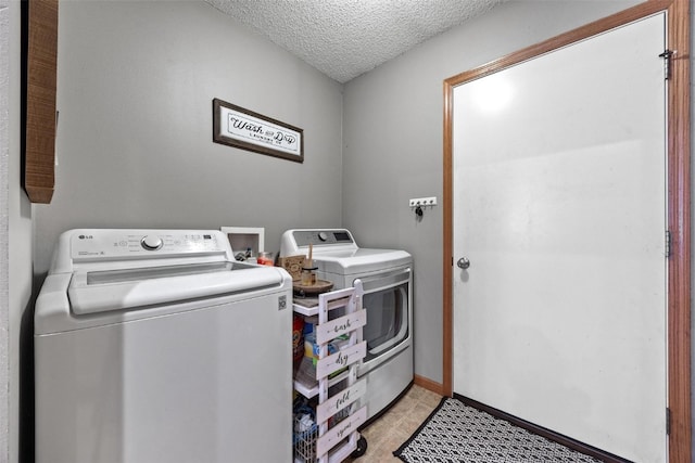 washroom featuring a textured ceiling, washer and clothes dryer, and light tile patterned flooring