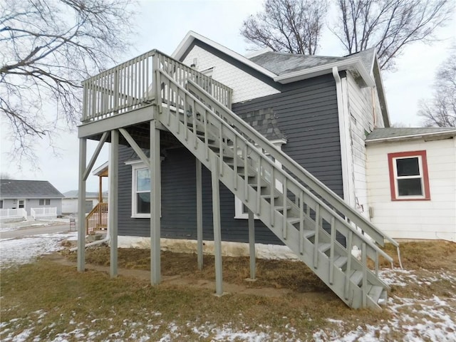 snow covered back of property with a deck