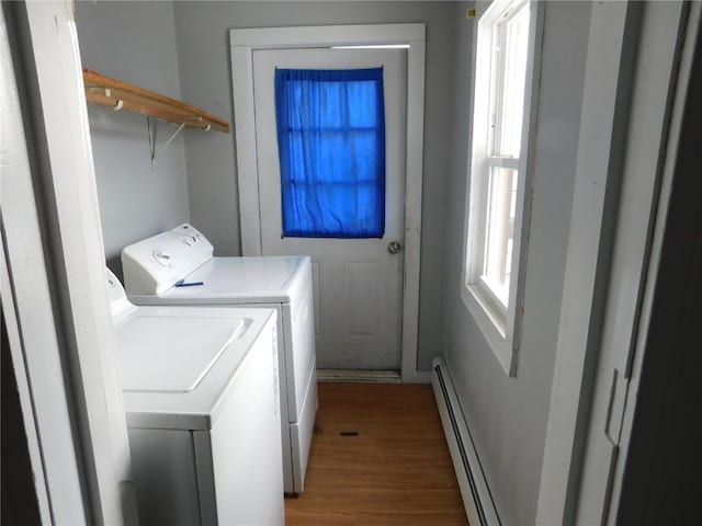 laundry room with washer and clothes dryer, a healthy amount of sunlight, hardwood / wood-style floors, and a baseboard heating unit