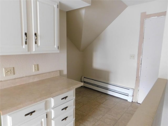 kitchen with white cabinets, baseboard heating, and vaulted ceiling