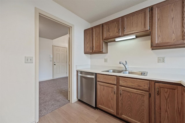 kitchen featuring sink, stainless steel dishwasher, a textured ceiling, and light wood-type flooring