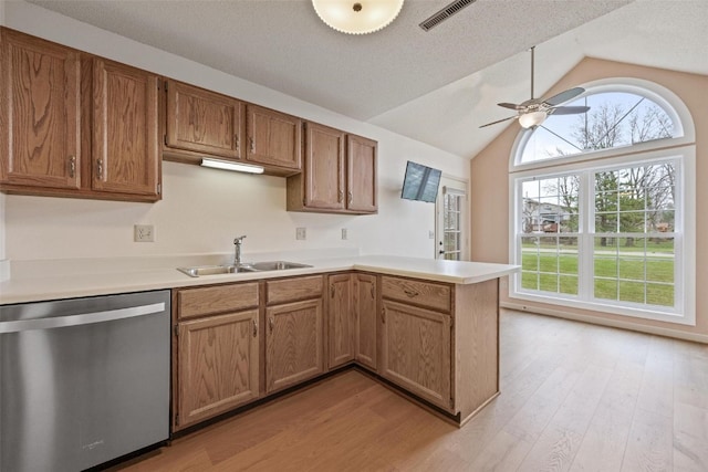 kitchen featuring dishwasher, sink, kitchen peninsula, light hardwood / wood-style floors, and vaulted ceiling