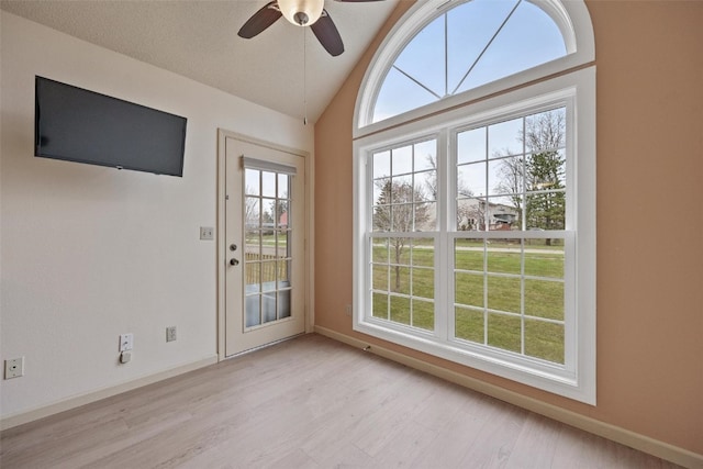 doorway to outside featuring a textured ceiling, ceiling fan, vaulted ceiling, and light wood-type flooring