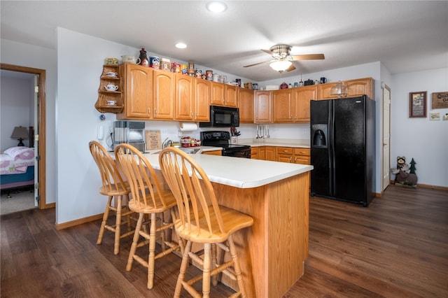 kitchen with black appliances, dark hardwood / wood-style floors, kitchen peninsula, and a breakfast bar area