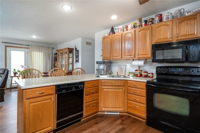 kitchen featuring black appliances, kitchen peninsula, sink, and dark wood-type flooring