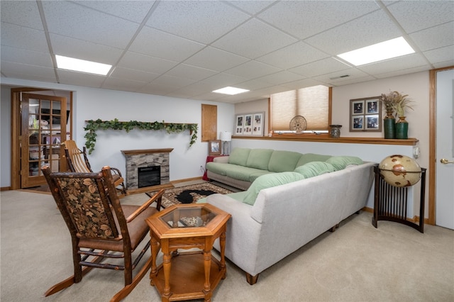 carpeted living room featuring a fireplace and a drop ceiling