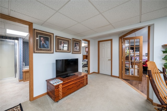 living room featuring a drop ceiling and carpet