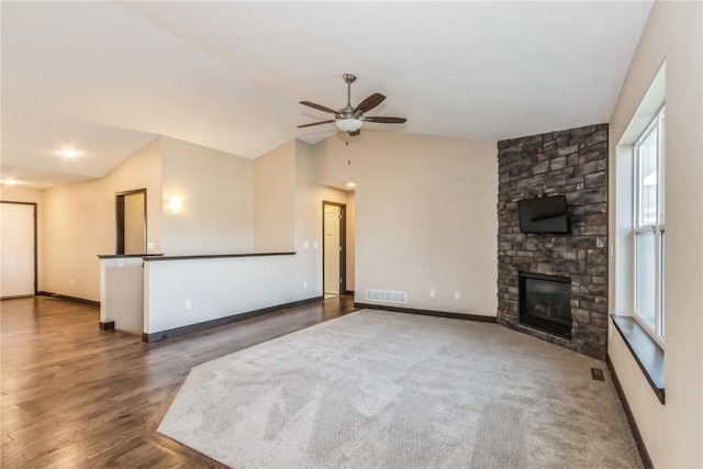 unfurnished living room featuring dark wood-type flooring, ceiling fan, lofted ceiling, and a stone fireplace