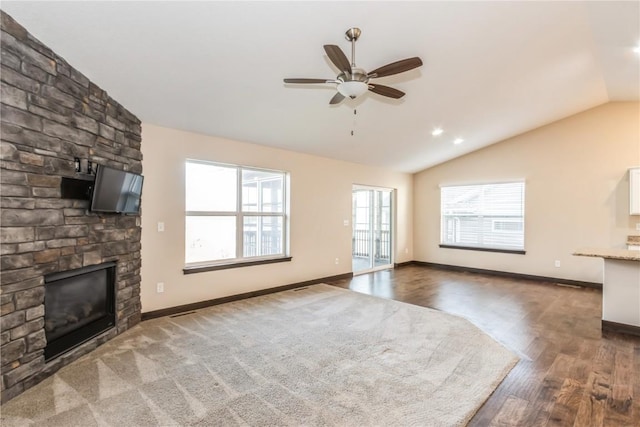 unfurnished living room featuring dark wood-type flooring, a large fireplace, ceiling fan, and vaulted ceiling