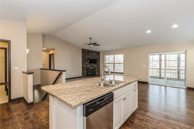 kitchen featuring sink, white cabinetry, a fireplace, an island with sink, and stainless steel dishwasher