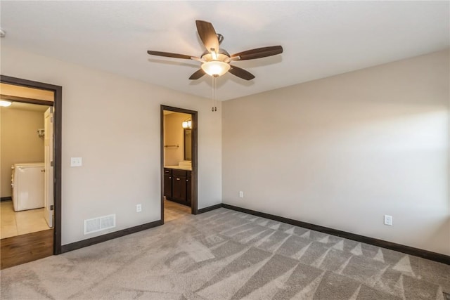 unfurnished bedroom with ceiling fan, a walk in closet, ensuite bath, and light carpet