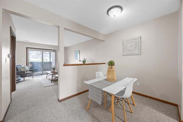 dining area with a textured ceiling and light colored carpet