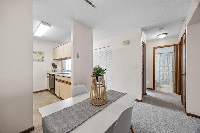 dining space with a textured ceiling, sink, and light carpet