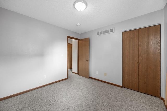 unfurnished bedroom with light carpet, a textured ceiling, and a closet