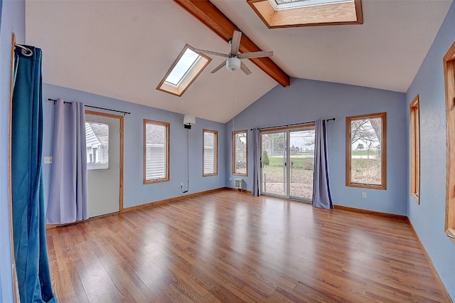 spare room featuring vaulted ceiling with skylight, plenty of natural light, ceiling fan, and light hardwood / wood-style flooring