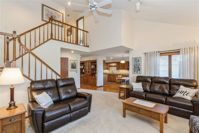 living room with ceiling fan, sink, high vaulted ceiling, and light wood-type flooring