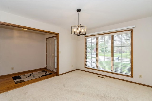empty room featuring visible vents, a notable chandelier, and baseboards