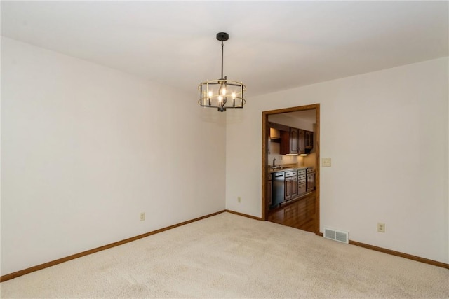 carpeted spare room with a sink, visible vents, a chandelier, and baseboards