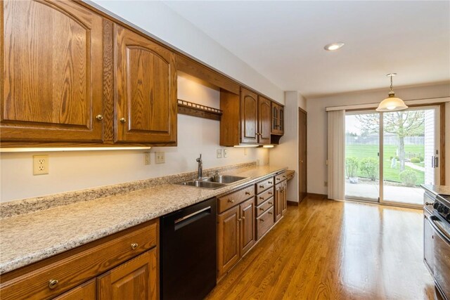 kitchen with black dishwasher, wood finished floors, brown cabinetry, and a sink