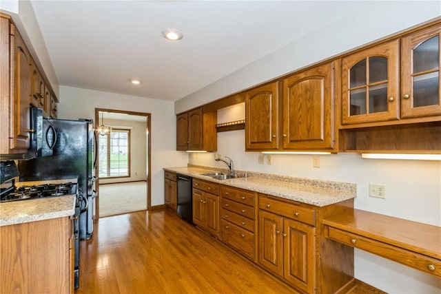 kitchen with black appliances, light wood-style flooring, brown cabinetry, and a sink