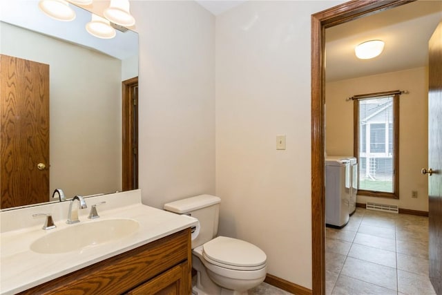bathroom with separate washer and dryer, tile patterned flooring, toilet, vanity, and baseboards