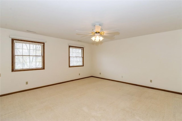 empty room featuring light colored carpet, ceiling fan, and baseboards