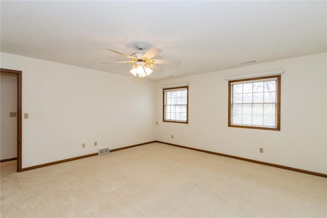 empty room featuring baseboards, visible vents, light carpet, and ceiling fan