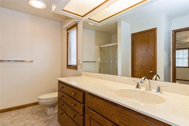 full bath with toilet, a stall shower, vanity, and baseboards