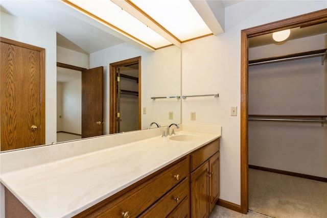 bathroom with a walk in closet, baseboards, and vanity