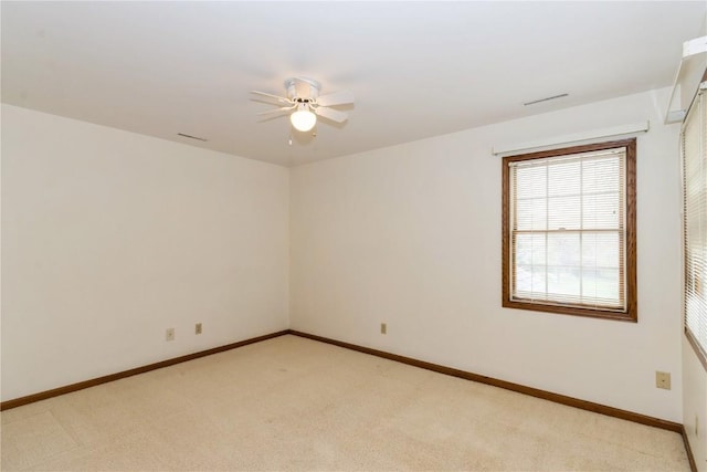 spare room with light colored carpet, a ceiling fan, and baseboards