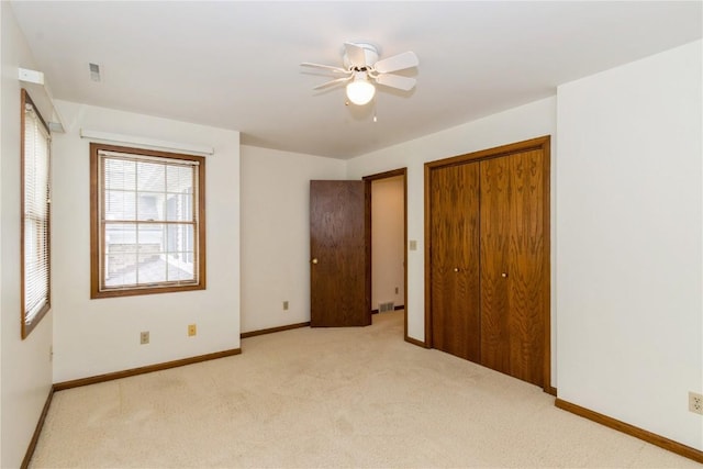 unfurnished bedroom featuring a closet, ceiling fan, visible vents, baseboards, and light colored carpet