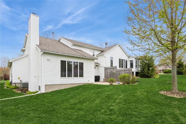 back of house featuring a chimney, a shingled roof, a patio, cooling unit, and a lawn