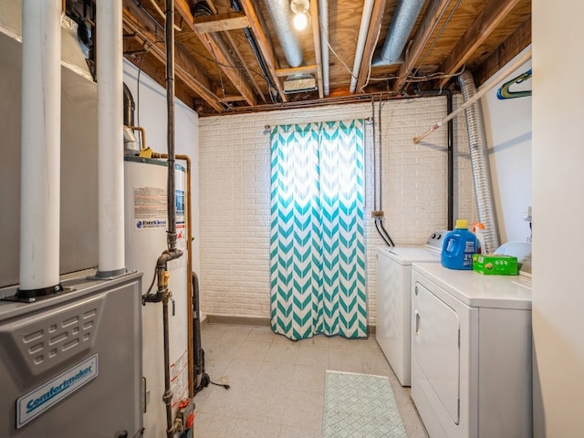 washroom featuring washing machine and clothes dryer, brick wall, and gas water heater