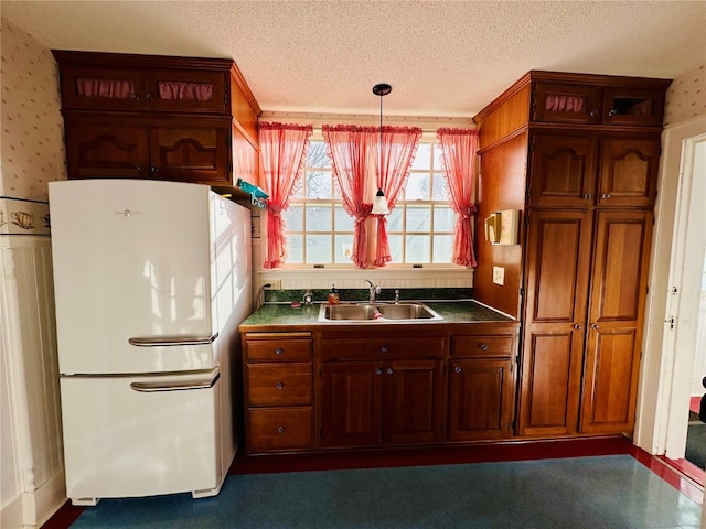 kitchen with pendant lighting, dark colored carpet, white refrigerator, sink, and a textured ceiling