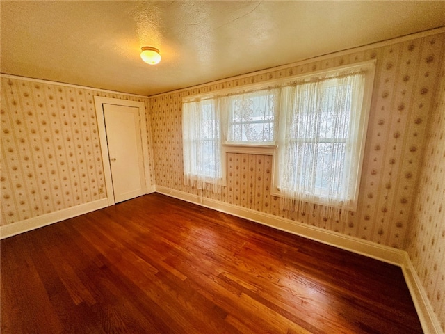 spare room featuring hardwood / wood-style floors, a textured ceiling, and crown molding