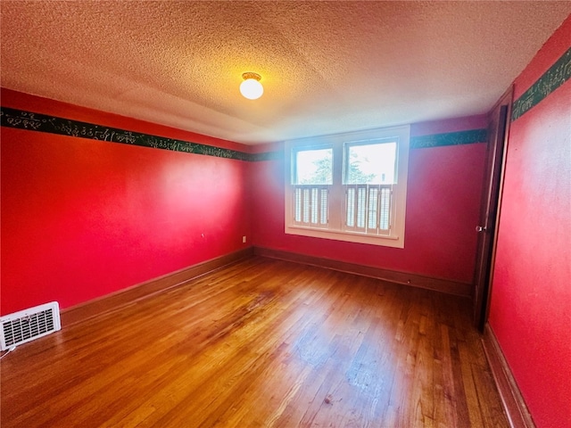 unfurnished room with hardwood / wood-style floors and a textured ceiling