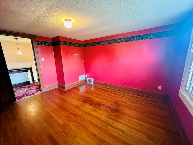 empty room with hardwood / wood-style floors and a textured ceiling