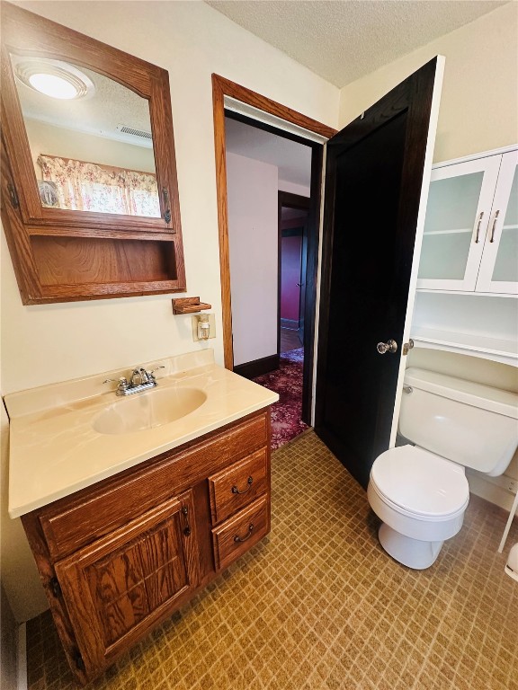 bathroom featuring vanity, toilet, and a textured ceiling