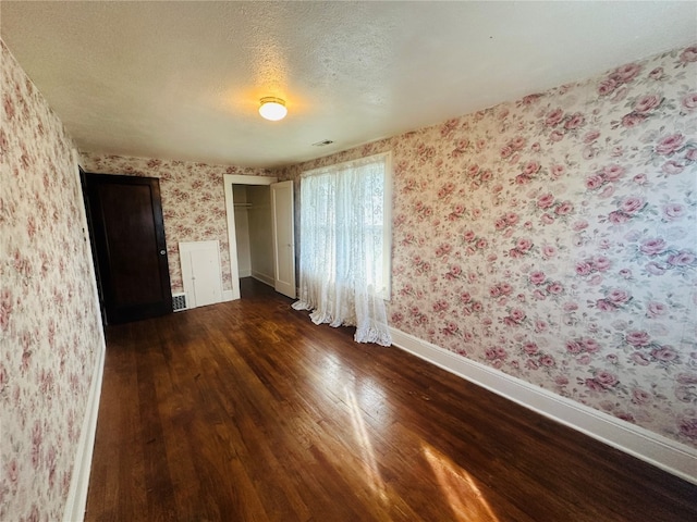 empty room featuring a textured ceiling and dark wood-type flooring