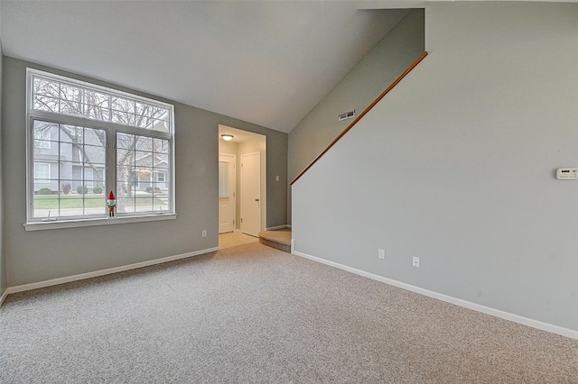 spare room with light colored carpet and vaulted ceiling