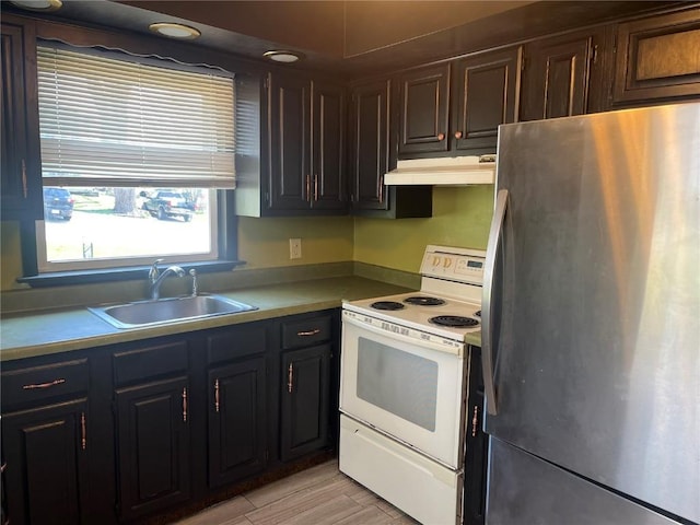 202 N Williams St, Anamosa, IA 52205 - kitchen featuring freestanding refrigerator, white range with electric stovetop, a sink, under cabinet range hood, and light wood finished floors