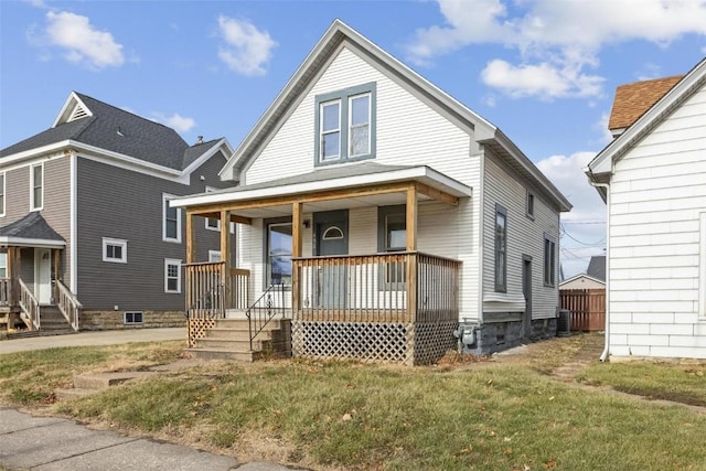 view of front facade with a front lawn, cooling unit, and covered porch