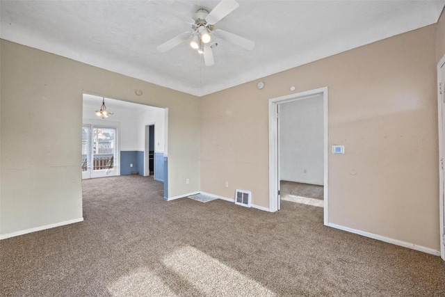 carpeted empty room featuring ceiling fan with notable chandelier