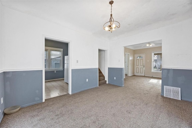 empty room featuring carpet flooring and a notable chandelier