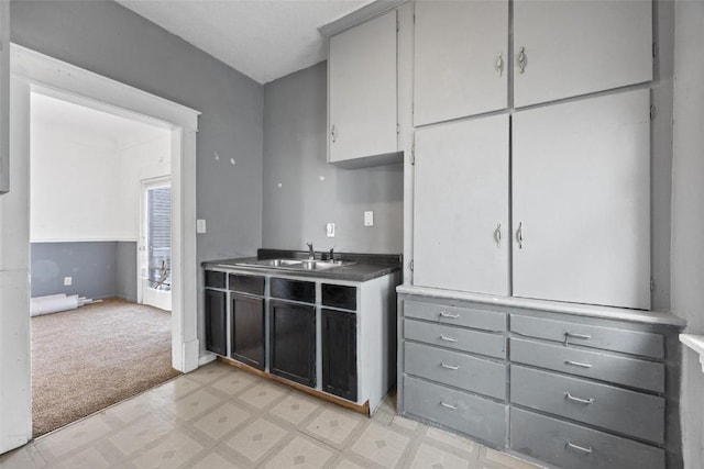 kitchen featuring light colored carpet, gray cabinetry, and sink